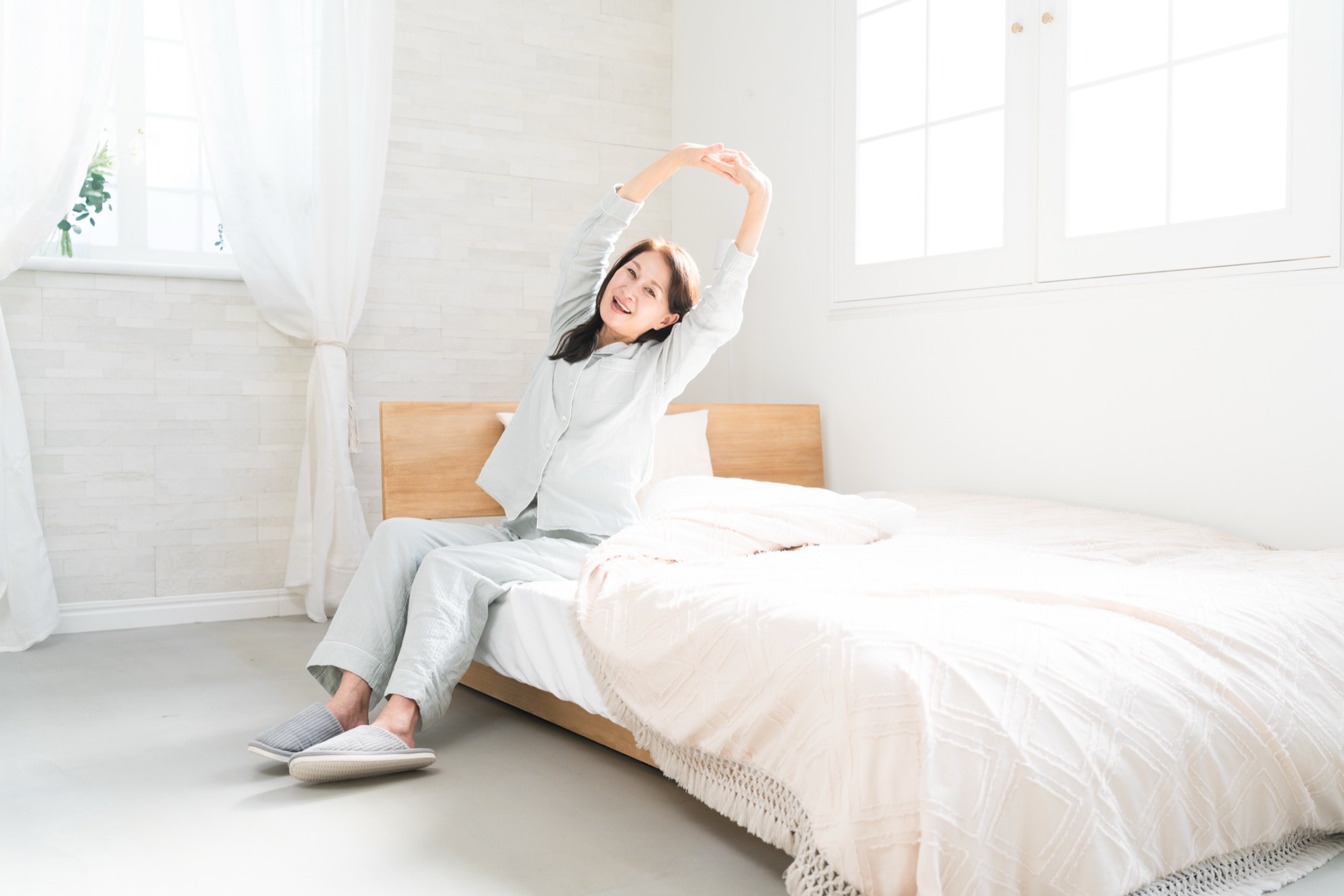 起床後ベッドで伸びをする女性